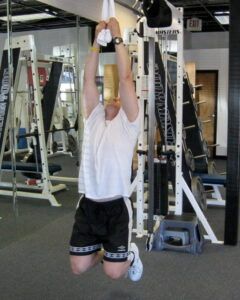 A man is kneeling down in a gym holding a towel over his head