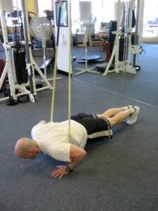 A man is doing push ups on a rope in a gym