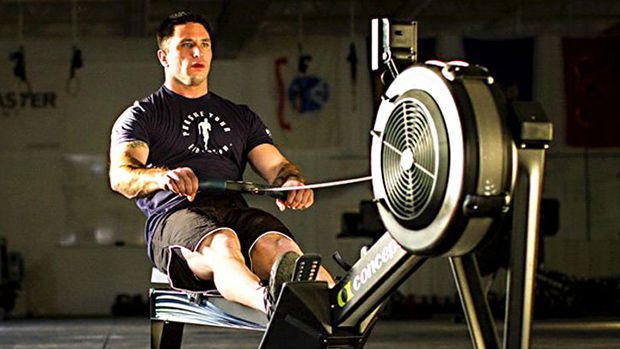 A man is riding a rowing machine in a gym.