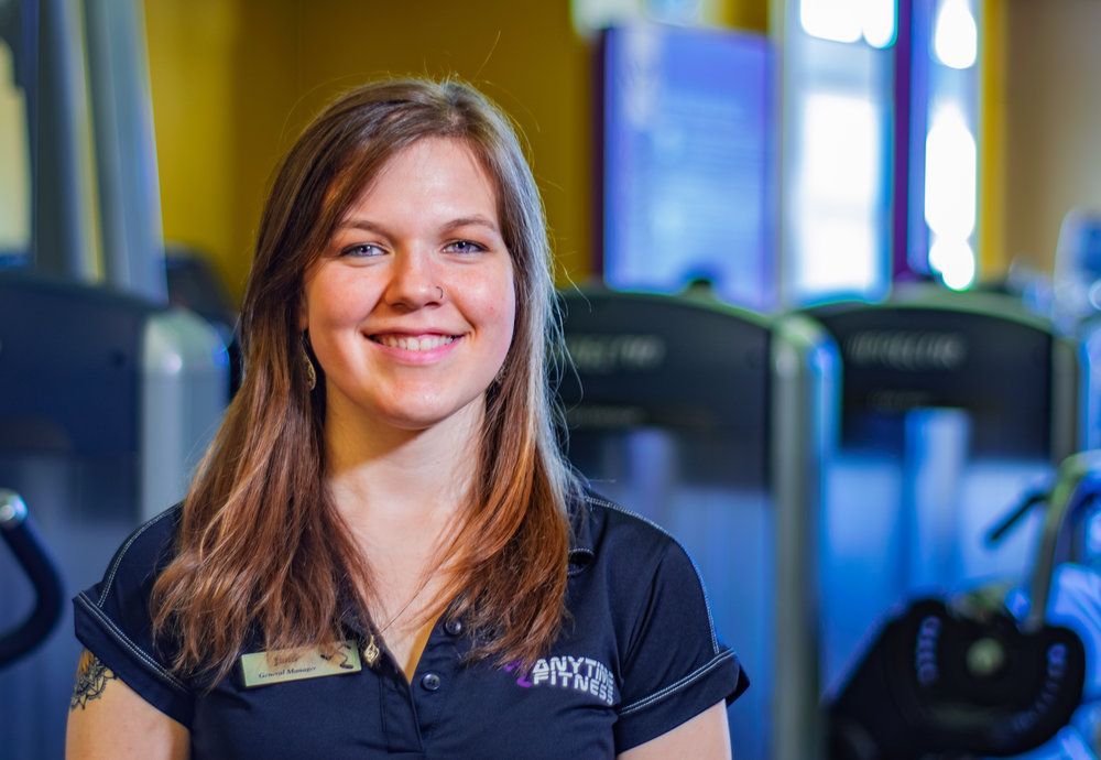 A woman in a black shirt is smiling in a gym.