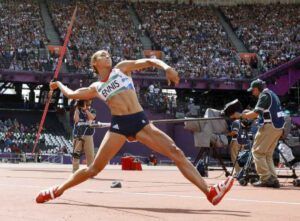 A female athlete is throwing a javelin in a stadium.