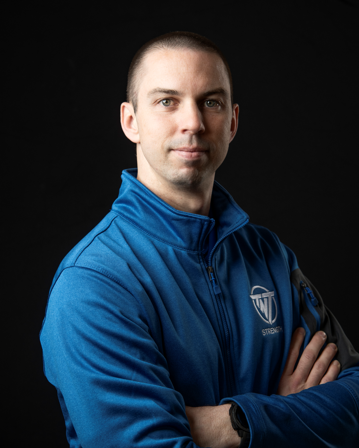 Jesse Schmidt, Strength Coach at TNT Strength in a TNT Strength blue jacket.