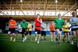 A group of people are running on a field in a gym.