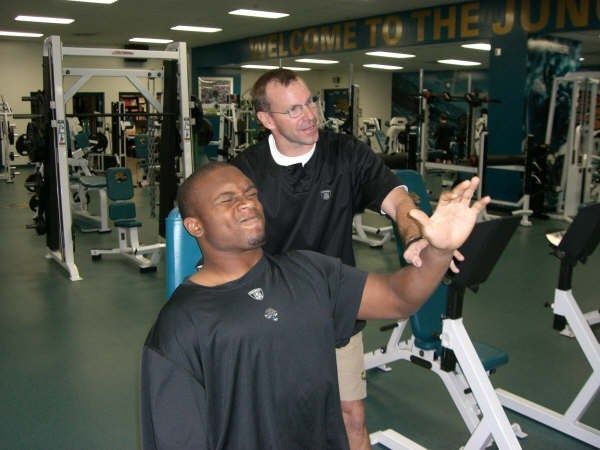 Two men in a gym with a sign that says welcome to the june