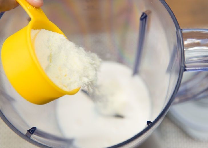 A yellow measuring cup is being poured into a blender