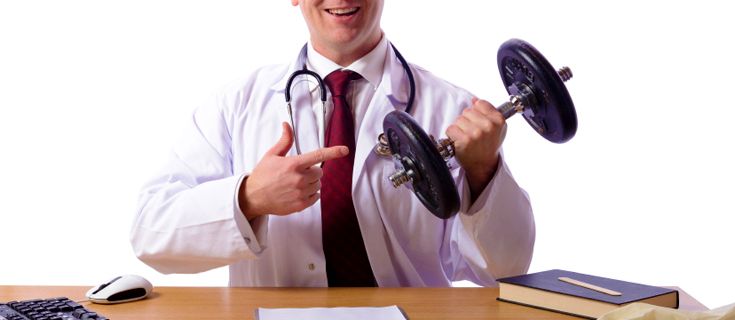 A doctor is sitting at a desk holding a dumbbell and pointing at it.