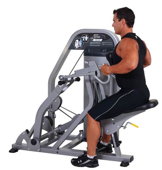 A man is sitting on a machine in a gym