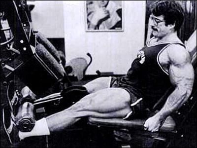 A man is doing leg extensions on a machine in a gym.