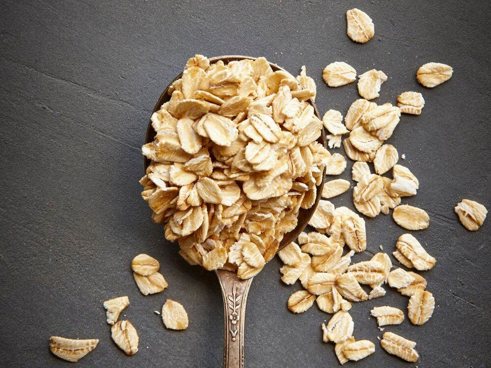 A wooden spoon filled with oats on a table