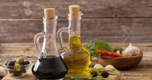 Two bottles of olive oil and balsamic vinegar on a wooden table.