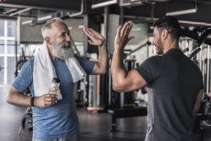 Two men are giving each other a high five in a gym.