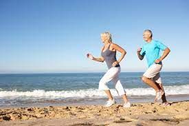 A man and a woman are jogging on the beach.