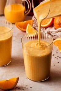 A person is pouring orange juice into a glass.