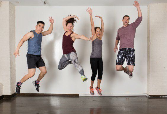 A group of people are jumping in the air in a gym.