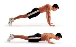 A shirtless man is doing push ups on his knees.