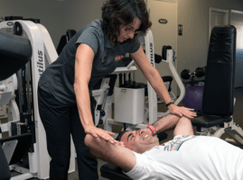 A woman is helping a man do exercises in a gym