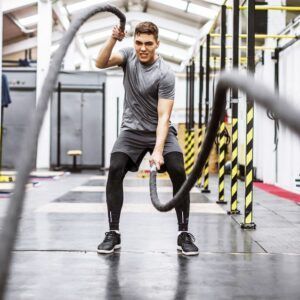 A man is holding a rope in a gym.