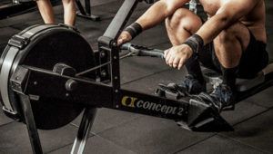 A man is sitting on a rowing machine in a gym.