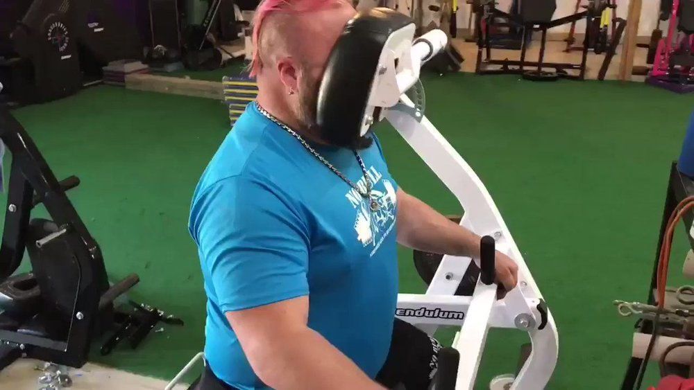 A man is sitting on a machine in a gym.