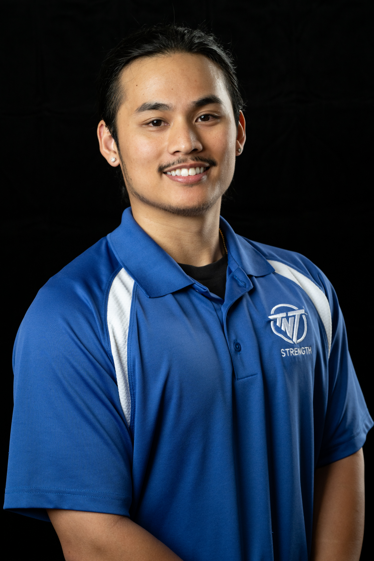 A young man wearing a blue and white polo shirt is smiling for the camera.