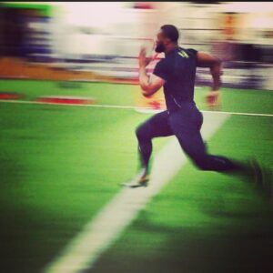 A man in a black shirt is running on a football field.