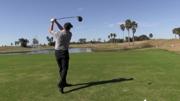 A man is swinging a golf club on a golf course