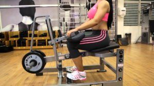 A woman is sitting on a bench in a gym.