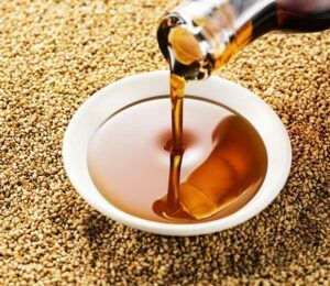 Sesame oil is being poured into a bowl of sesame seeds.