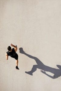 A man is standing on a white surface with his shadow on the ground.