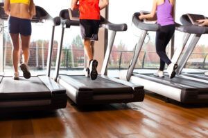 Three people are running on treadmills in a gym.