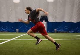 A woman is running on a field in an indoor gym.