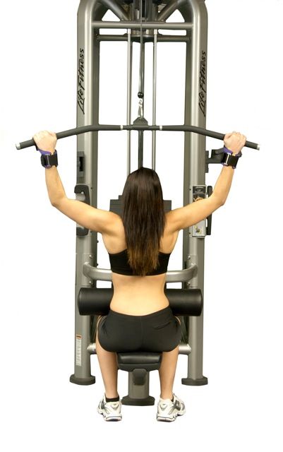 A woman is sitting on a machine with her back to the camera.