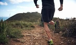 A man is running on a dirt trail on top of a hill.