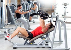 A man is lifting a barbell in a gym.