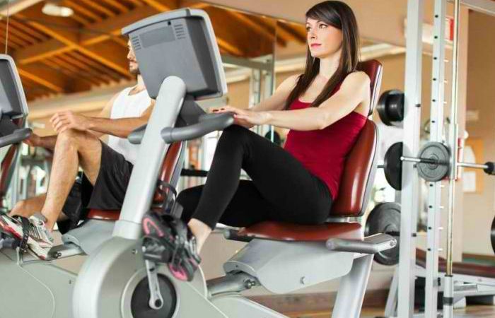 A woman is sitting on an exercise bike in a gym.