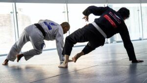 Two men are practicing jiu jitsu on a mat in a gym.