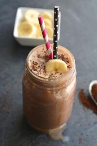 A chocolate banana milkshake in a mason jar with a straw.