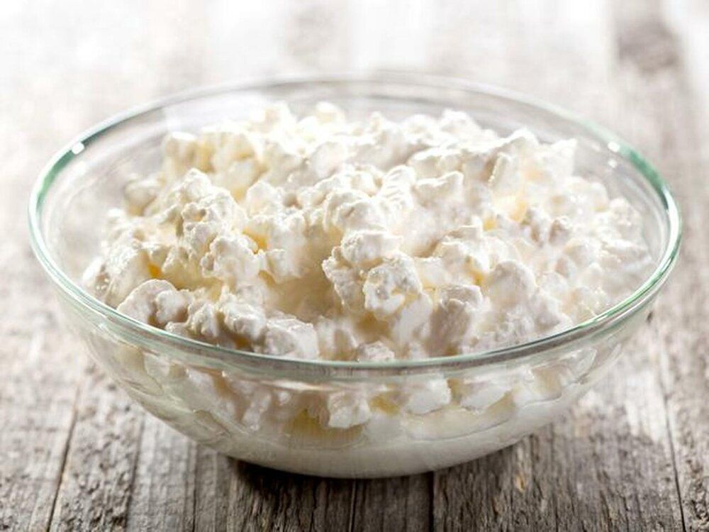 Cottage cheese in a glass bowl on a wooden table.