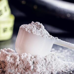 A scoop of protein powder is sitting on top of a pile of powder.