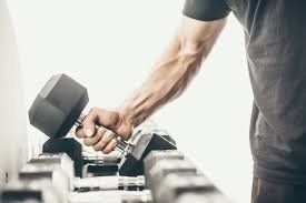 A man is holding a dumbbell in his hand in a gym.