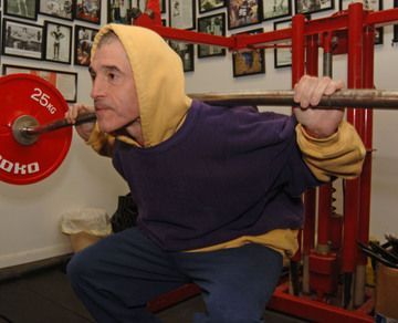 A man squatting with a barbell that says 25kg on it