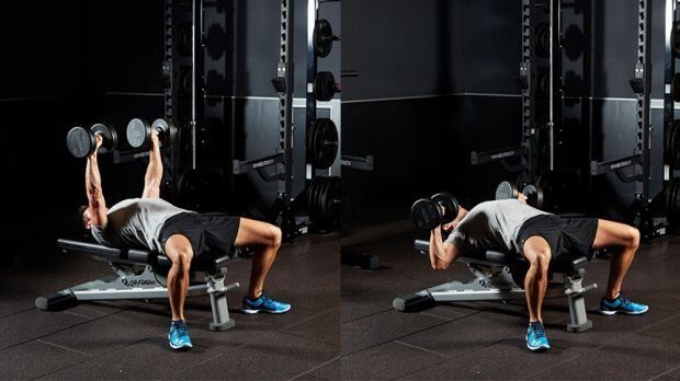 A man is lifting dumbbells on a bench in a gym.