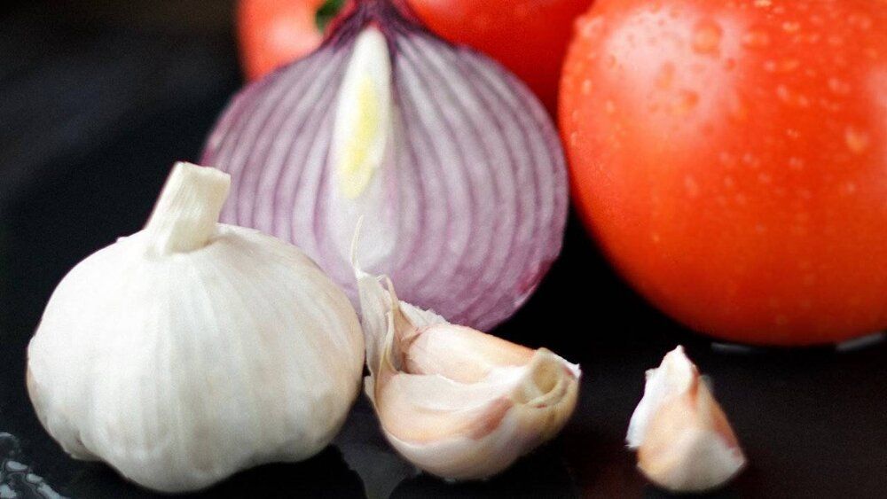 Garlic tomatoes and onions on a black surface