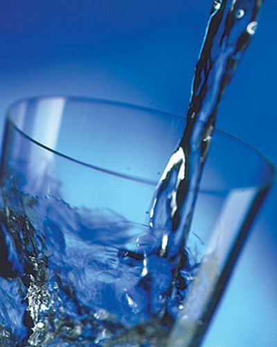 Water is being poured into a glass on a blue background