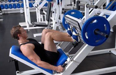 A man is using a leg press machine in a gym.