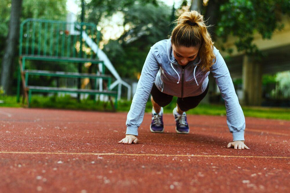 A woman is doing push ups on a track.