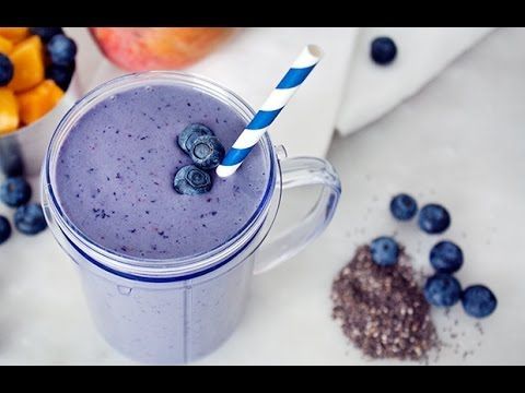 A purple smoothie with blueberries and a blue and white striped straw