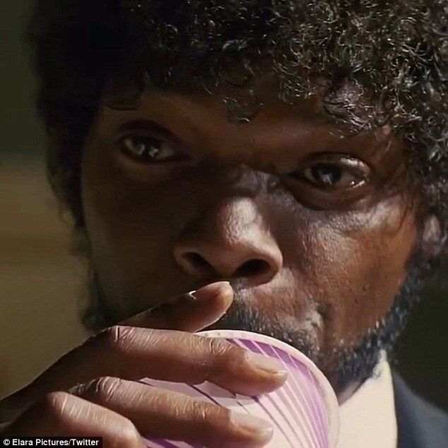 A man with curly hair is drinking from a pink cup