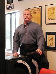 A man is standing next to a speaker in a room.