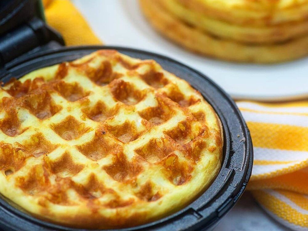 A close up of a waffle in a waffle maker on a table.